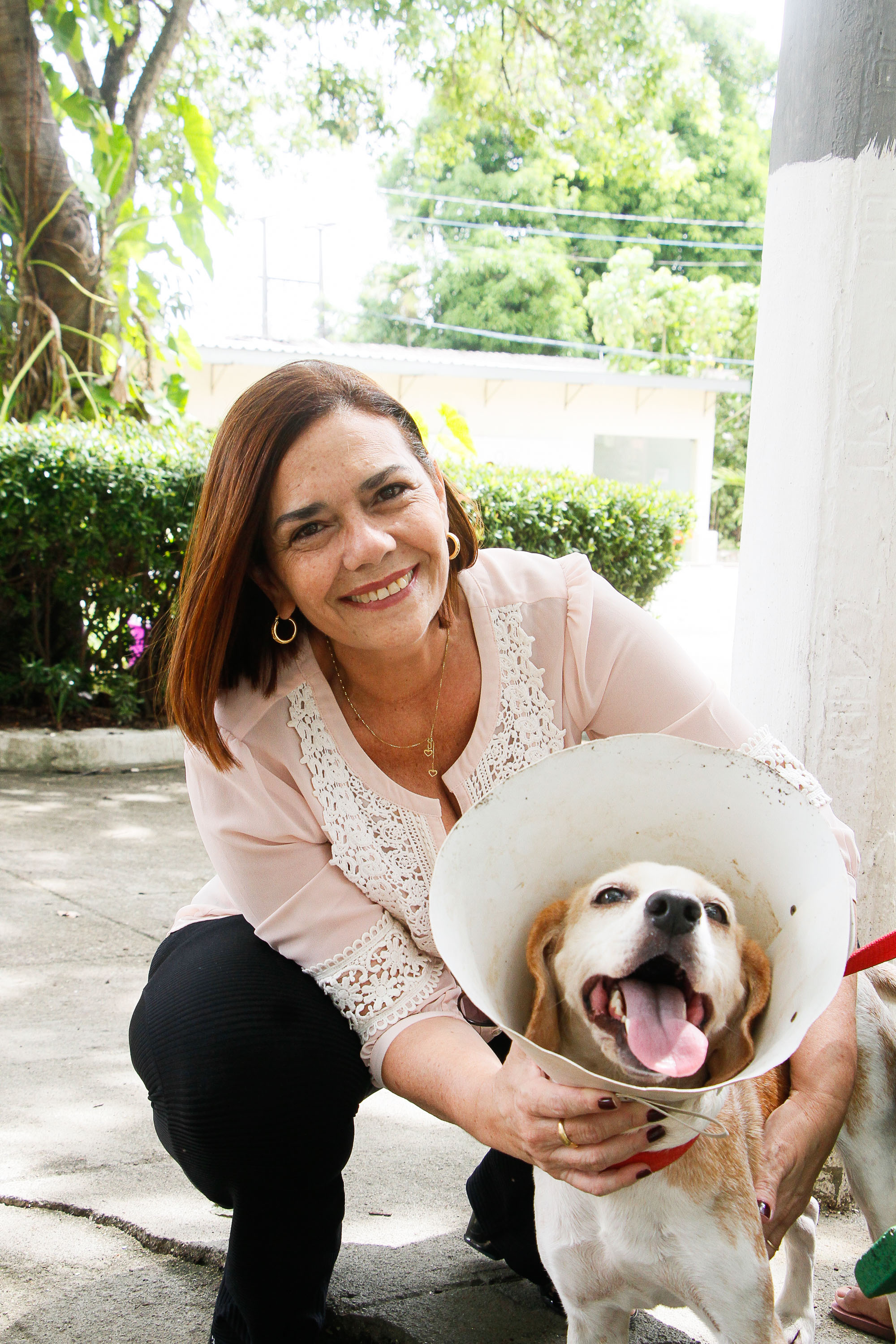 mulher de cócoras ao lado de cachorro sorrindo para a foto